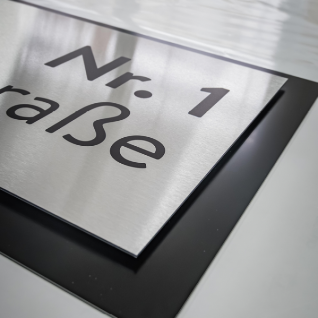Das Haustürschild aus Alu-Dibond gebürstet. Hochwertig, wetterbeständig und stabil.