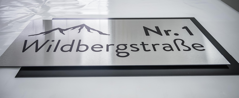 Alu gebürstetes Dibond bedruckt im Plattendirektdruck. Ein haltbares, wetterresistenten, edles Fassadenschild